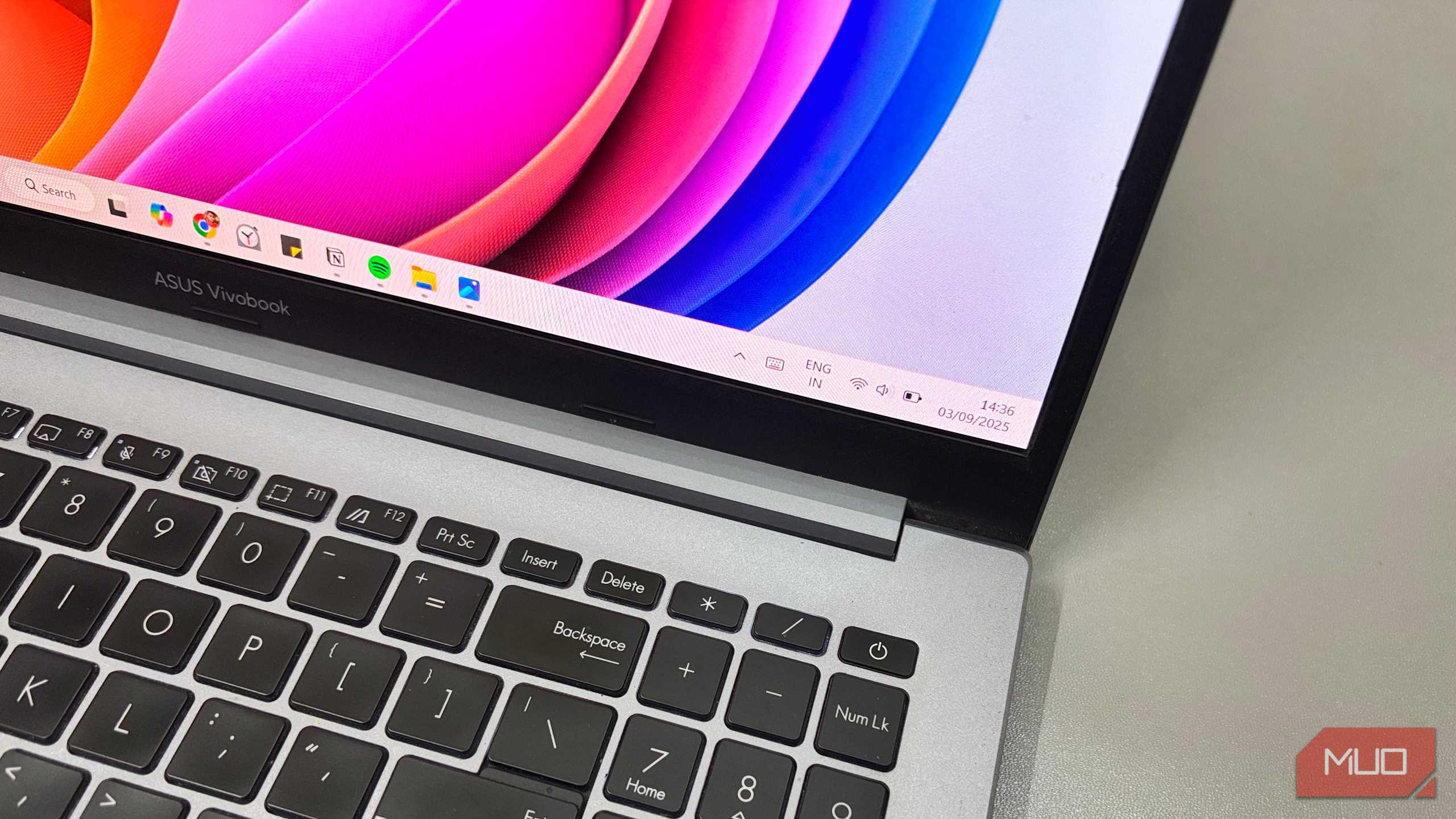 لپ‌تاپ ASUS Vivobook که دسکتاپ ویندوز ۱۱ را با نوار وظیفه و پس‌زمینهٔ رنگارنگ صفحه نشان می‌دهد