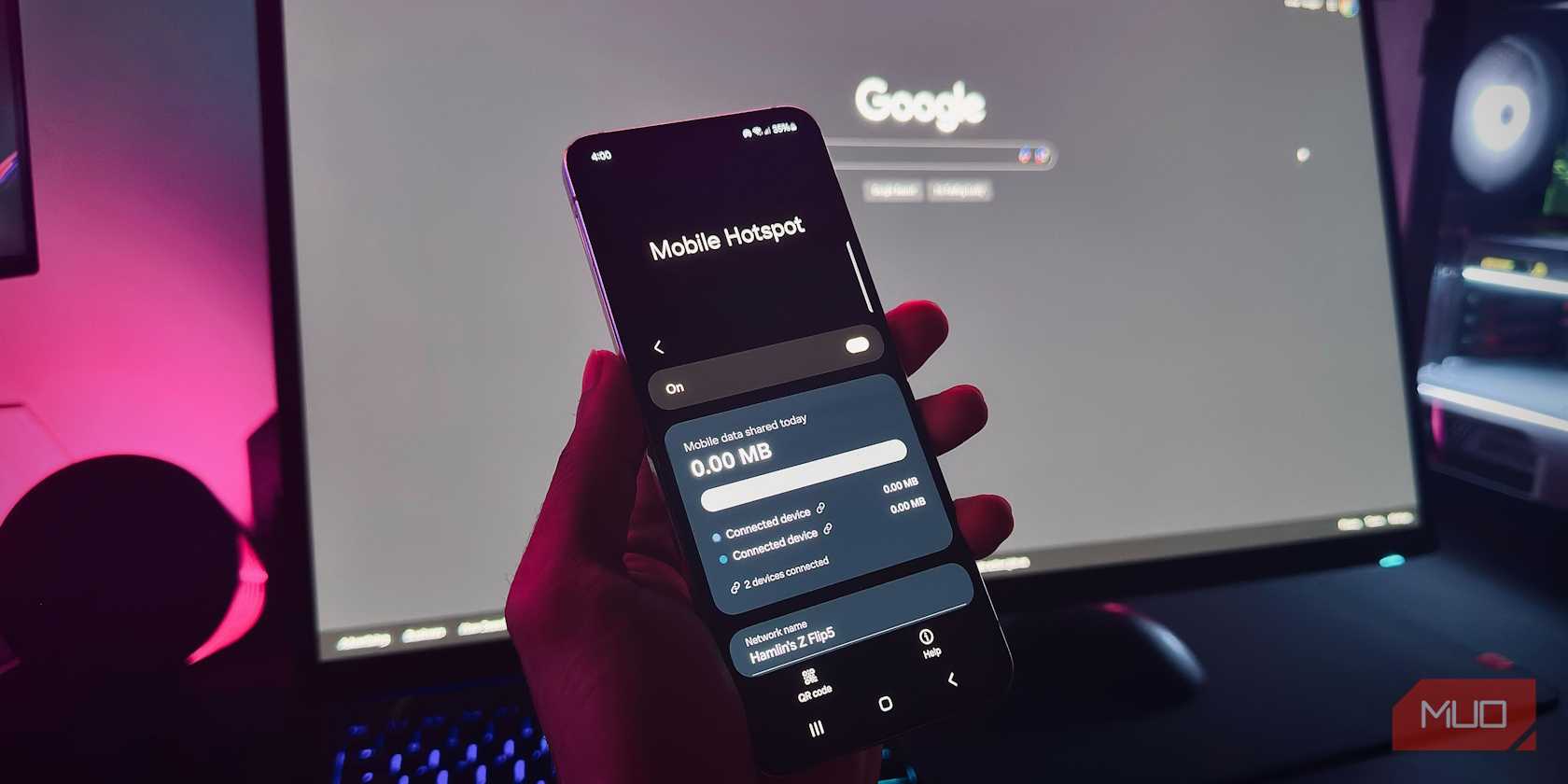 دست نگه‌دارنده یک گوشی اندروید که ویژگی هات‌اسپات موبایل را در مقابل مانیتور کامپیوتر نشان می‌دهد