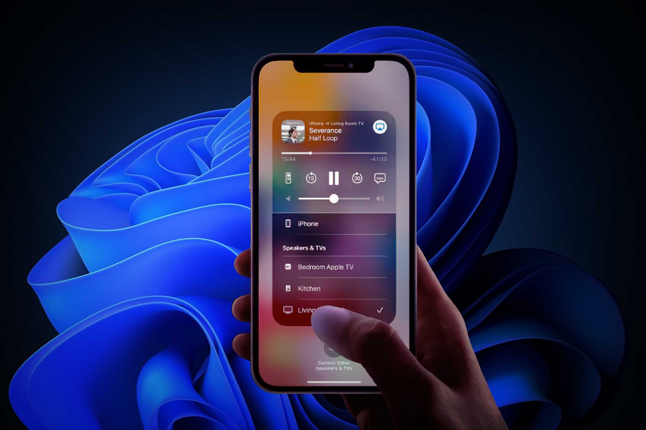یک فرد در حال نگه داشتن آیفون با رابط AirPlay روی نمایشگر و یک تصویر پس‌زمینه ویندوز 11