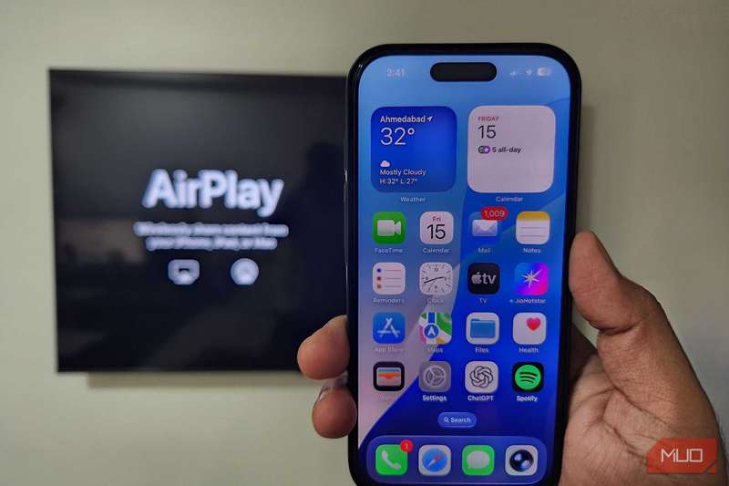 آیفون در دست با تلویزیون که AirPlay را در پس‌زمینه نشان می‌دهد