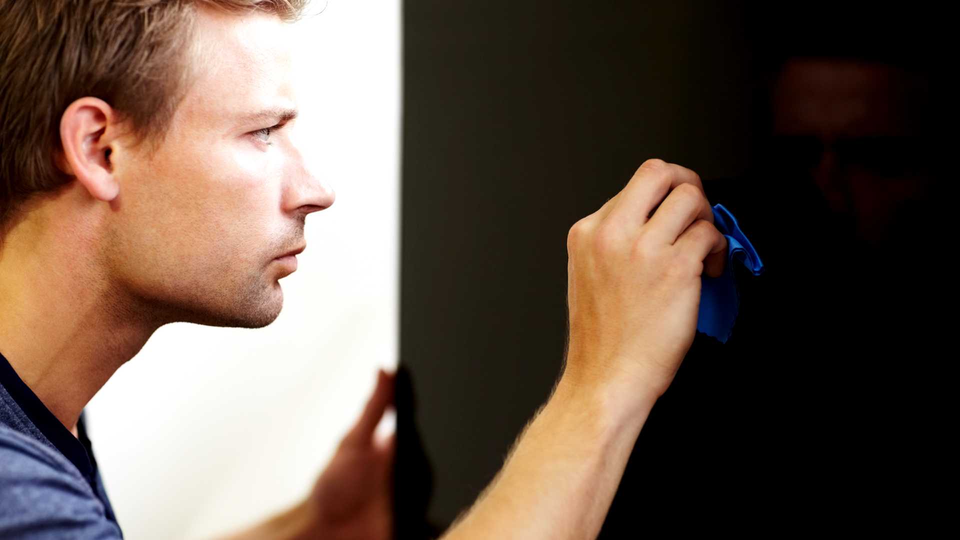 مردی که به دقت تلویزیون هوشمند را با دستمال تمیز میکند