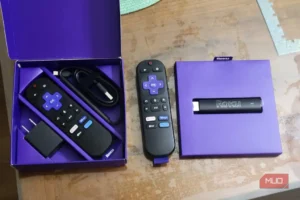 یک Roku stick در کنار یک ریموت کنترل و یک ریموت کنترل دیگر