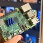 برد Raspberry Pi 4 جلوی یک تلویزیون هوشمند در دست گرفته شده است.