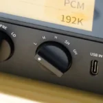 نمای نزدیک از کلید Gain روی DAC مدل Fiio K15 در کنار هدفون.
