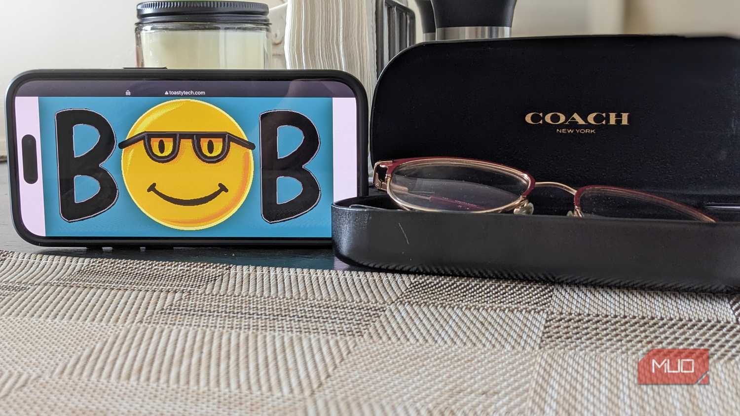 لوگوی Microsoft Bob روی گوشی در کنار یک قاب عینک