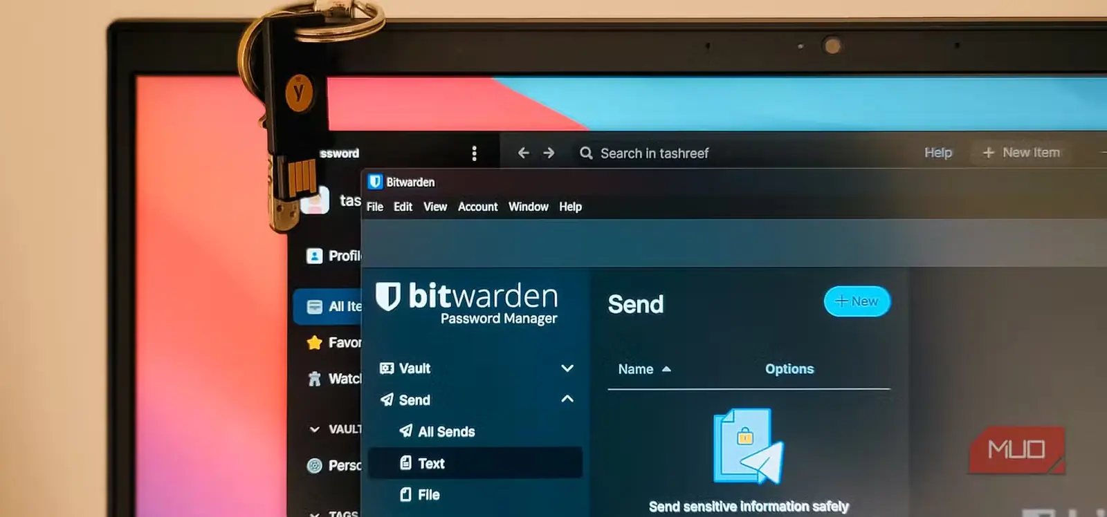 برنامههای Bitwarden و 1Password در پنجرههای همپوشان در ویندوز ۱۱ باز شدهاند با یک YubiKey آویزان روی درِ لپتاپ