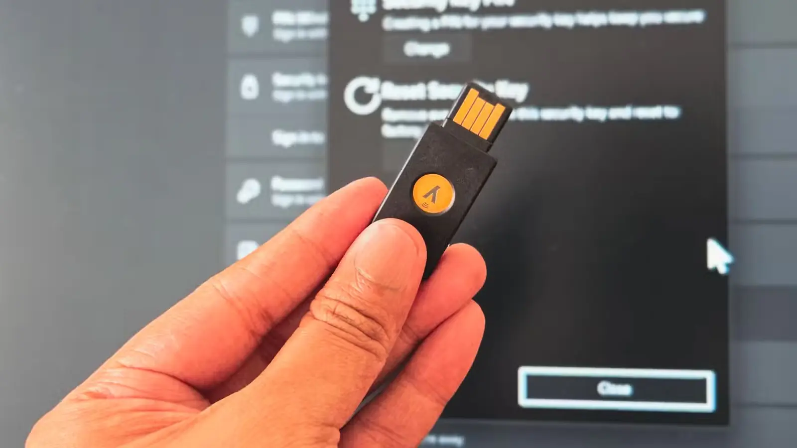 فردی کلید YubiKey را در مقابل مانیتور دسکتاپ ویندوز ۱۱ در دست دارد
