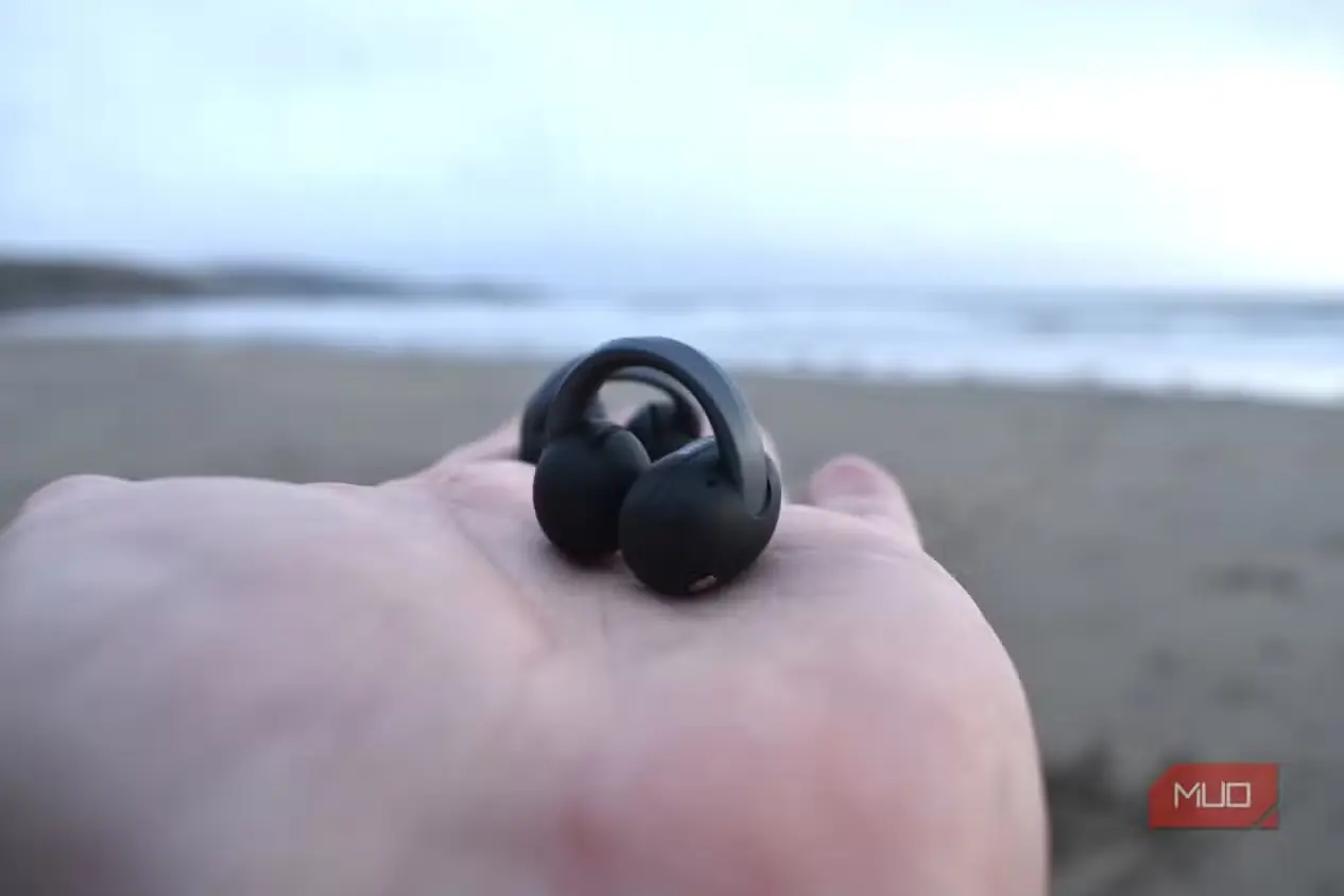 هر دو ایرباد Anker Soundcore AeroFit 2 در دست، با پسزمینهٔ دریا