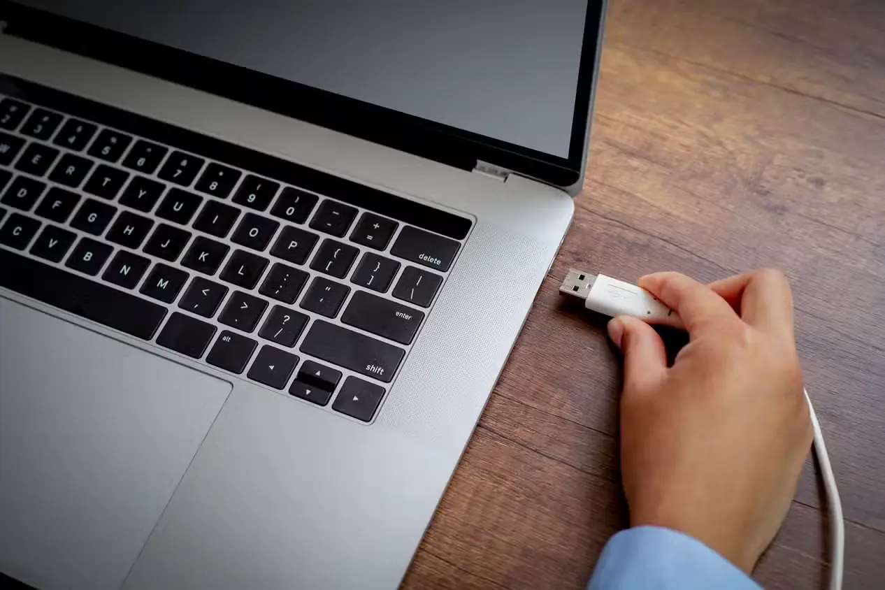 فردی در حال اتصال کابل USB-A به درگاه لپتاپ
