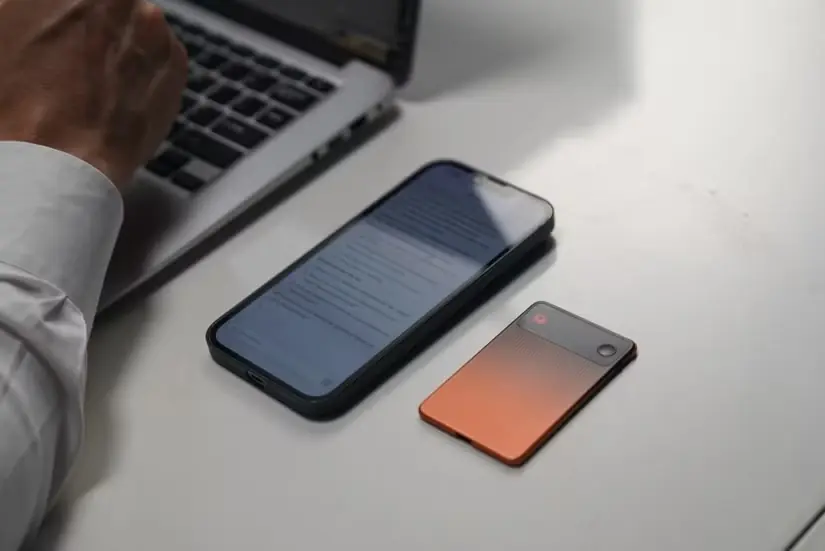 مردی در حال کار با لپتاپ، در کنار گوشی و دستگاه EurekaMind 2.0 AI Note