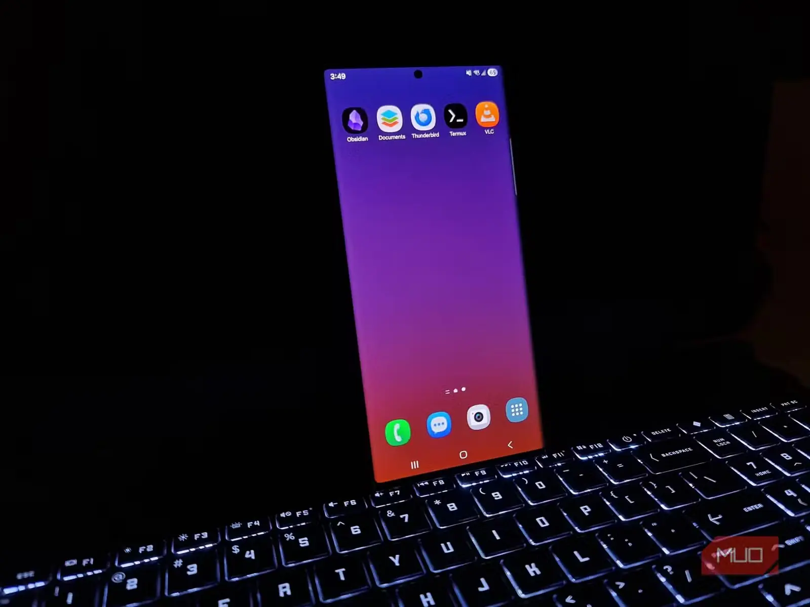 گوشی Samsung Galaxy Note20 Ultra در حال نمایش پنج برنامهٔ آزمایششدهٔ Android در کنار صفحهنمایش خاموش لپتاپ