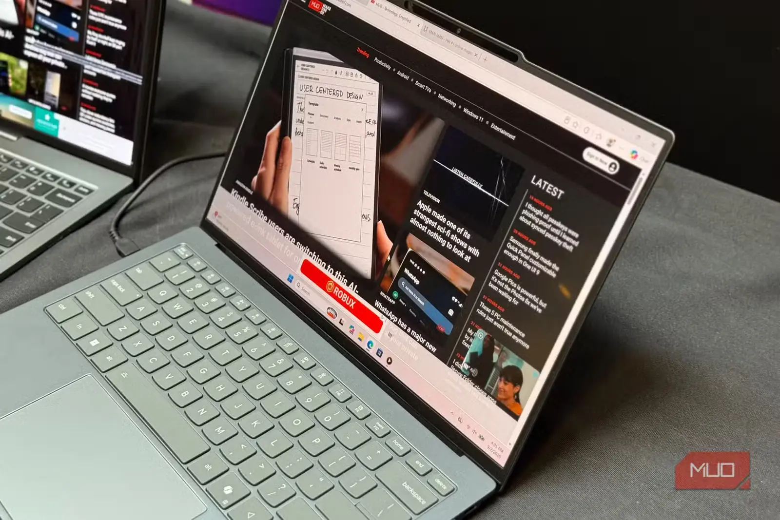 نمای نزدیک لپتاپ سبز مریمگلی Lenovo هنگام مرور صفحهٔ اصلی MakeUseOf