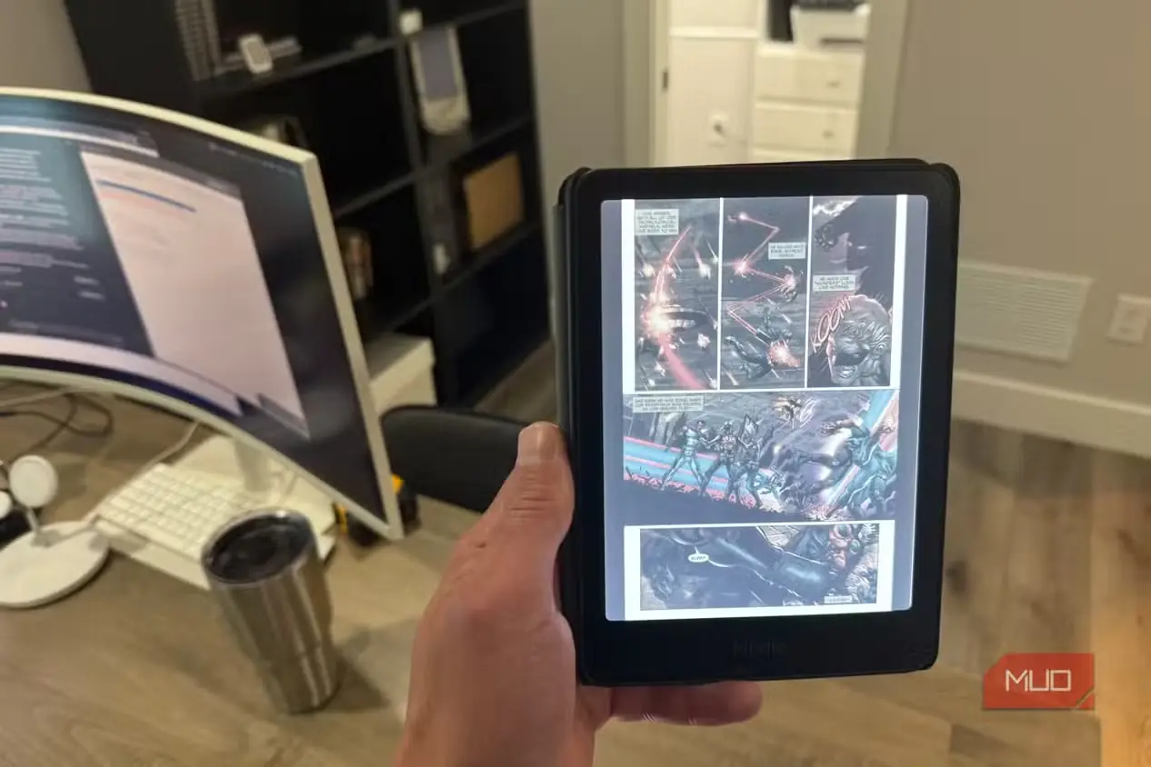 Kindle Colorsoft در دست کاربر و نمایش صفحه کمیک در دفتر کار خانگی