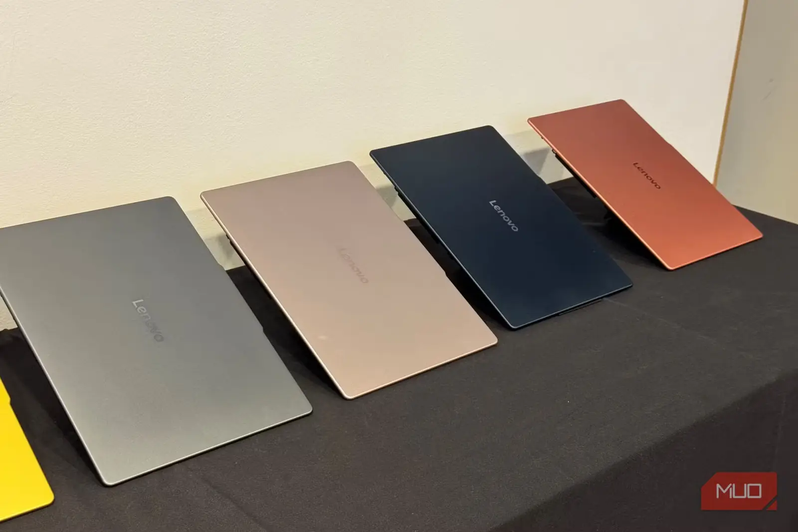 درب لپتاپهای Lenovo به رنگهای خاکستری، شنی، سرمهای و مسی روی میز سیاه