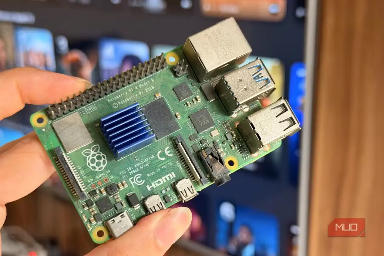 برد Raspberry Pi 4 در دست، مقابل تلویزیون هوشمند