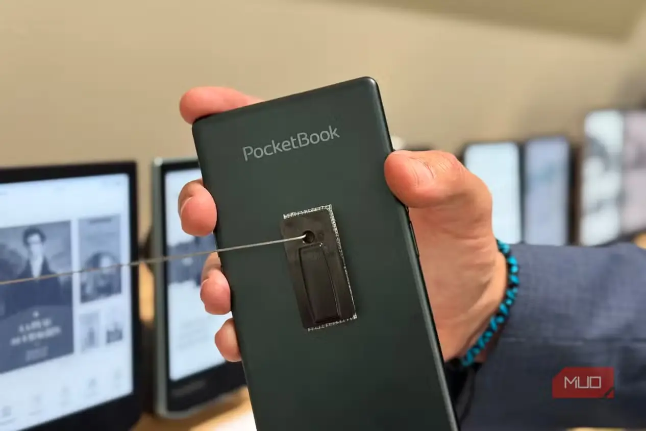 نمای پشت PocketBook Q سبزرنگ در دست، با کتابخوانهای محو در پسزمینه