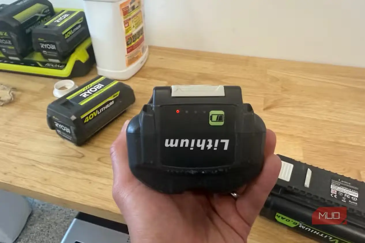 دستی در حال نگهداشتن باتری متفرقه 40V سازگار با Ryobi و نمایش چراغهای نشانگر شارژ