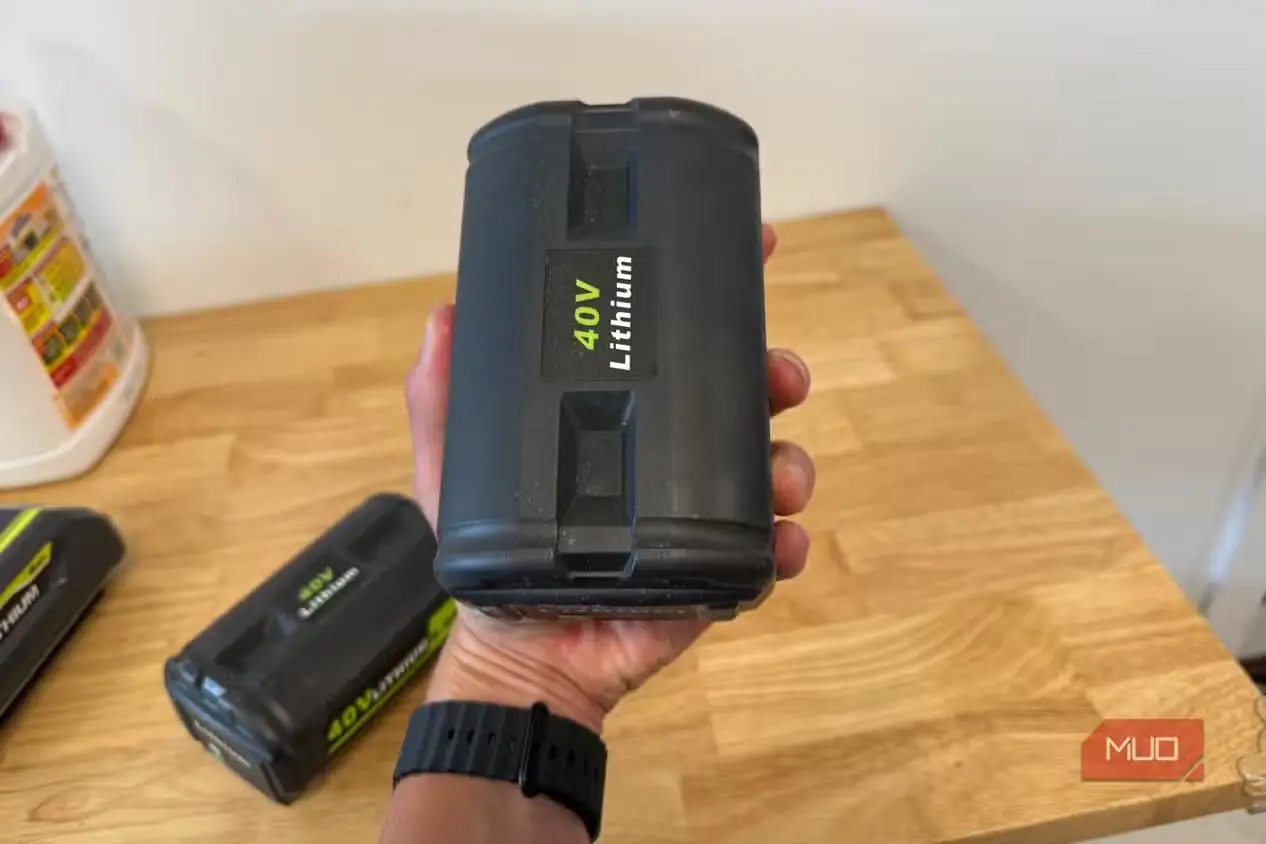 دستی در حال نگهداشتن عمودی باتری لیتیومی متفرقه 40V سازگار با Ryobi بالای میز کار
