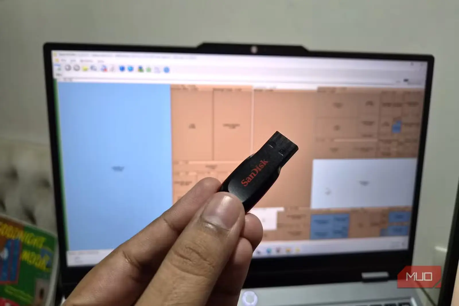 دستی در حال نگهداشتن حافظهٔ USB جلوی لپتاپ
