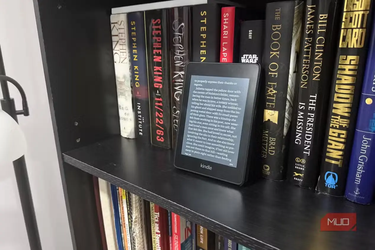 دستگاه Kindle Paperwhite روی قفسهٔ سیاه کتابها