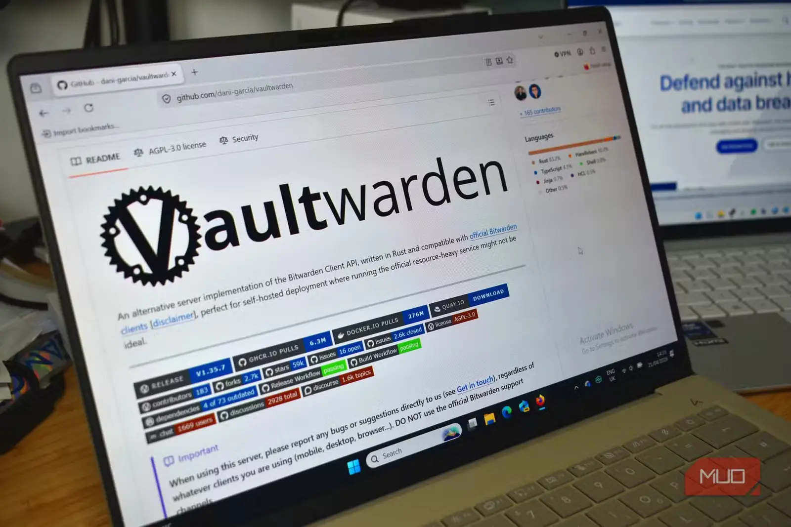صفحهٔ GitHub مربوط به Vaultwarden روی لپتاپ، با Bitwarden در پسزمینه