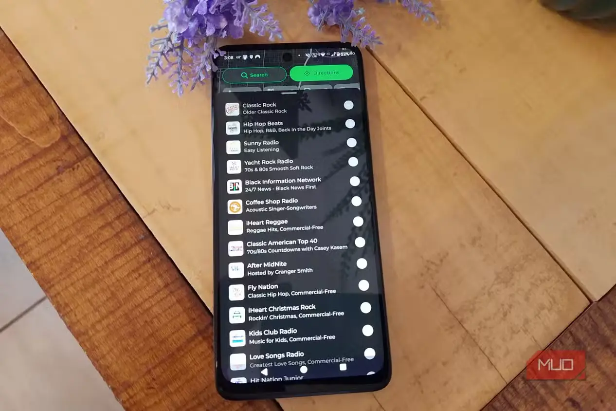 گوشی هوشمند روی میز چوبی در حال نمایش فهرست ایستگاههای Live Radio در MapQuest