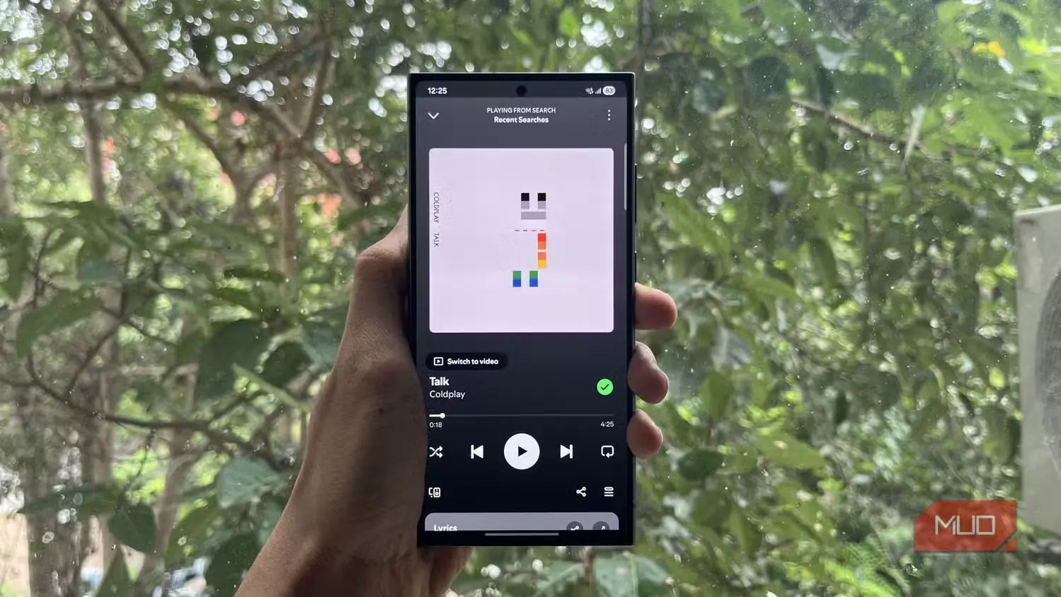 فردی در حال نگهداشتن گوشی Samsung با برنامهٔ Spotify باز