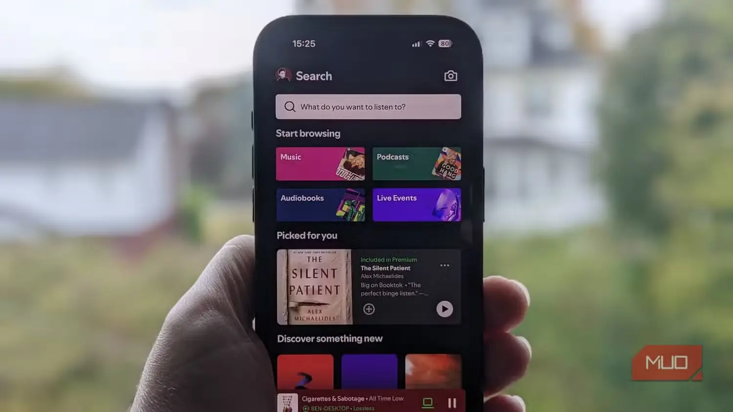 صفحهٔ اصلی Spotify روی یک iPhone در برابر پنجره